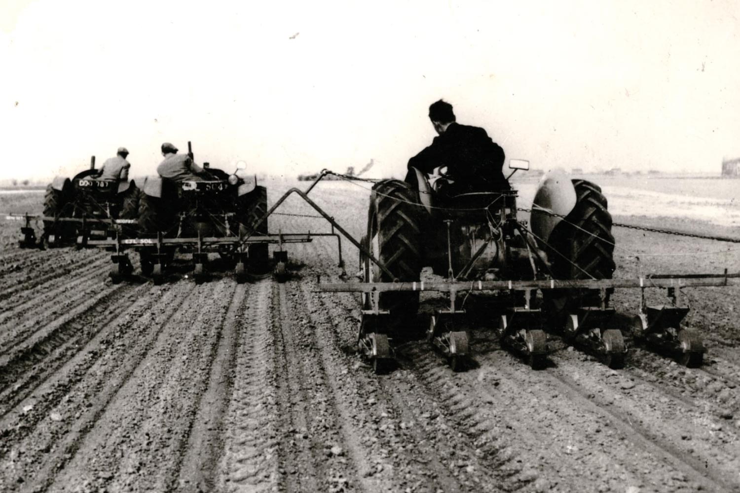 Black and white historic photo of tractors ploughing field